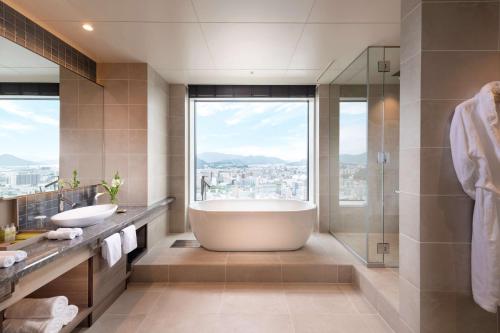 a bathroom with a large tub and a shower at Hilton Hiroshima in Hiroshima