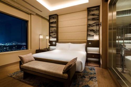 a bedroom with a bed and a bathroom with a window at Hilton Hiroshima in Hiroshima