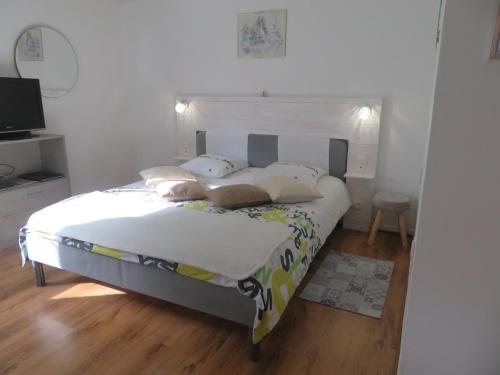 una camera da letto con letto, lenzuola e cuscini bianchi di Les Renardeaux a Malmedy