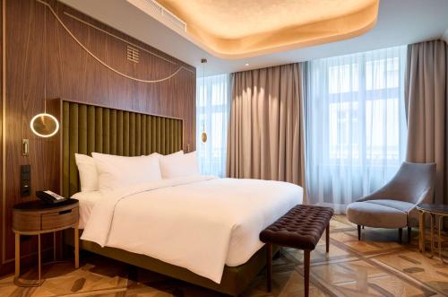 a bedroom with a large white bed and a chair at Hotel Saski Krakow Curio Collection by Hilton in Kraków