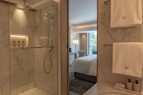 a bathroom with a shower and a toilet and a bed at Kwetu Nairobi, Curio Collection By Hilton in Nairobi