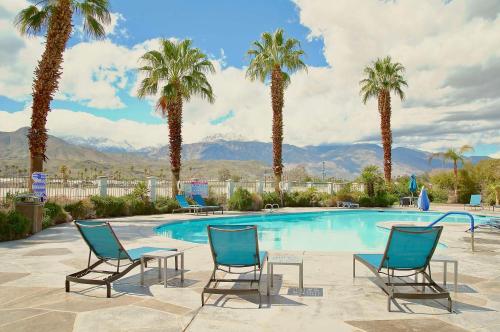 a swimming pool with two chairs and palm trees at Hampton Inn & Suites Cathedral City in Cathedral City