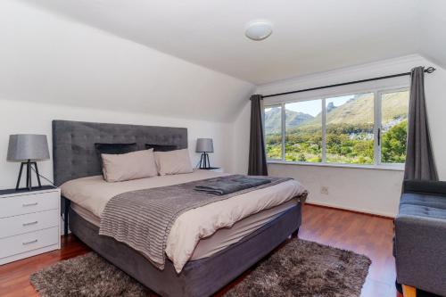 a bedroom with a bed and a large window at Hout Bay Gem - Elise Way in Hout Bay