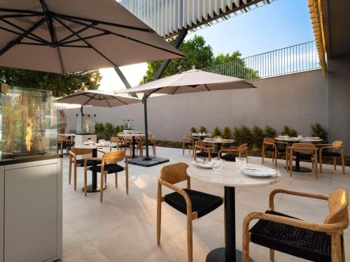 a patio with tables and chairs and umbrellas at Hilton Garden Inn Evora in Évora