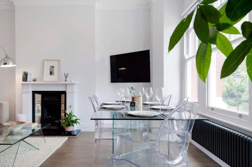 une salle à manger avec une table et des chaises en verre dans l'établissement Modern and Bright Highgate Gem, à Londres