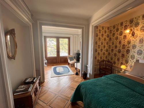 a bedroom with a bed with a green comforter and a window at Le Faubourg 29 in Neuchâtel