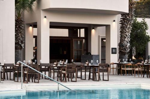 a restaurant with tables and chairs next to a swimming pool at Lindian Village All Inclusive Resort Rhodes,Curio Collection in Kiotari
