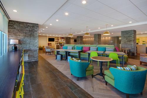 a lobby with blue and green chairs and tables at Home2 Suites By Hilton Shepherdsville Louisville South in Shepherdsville