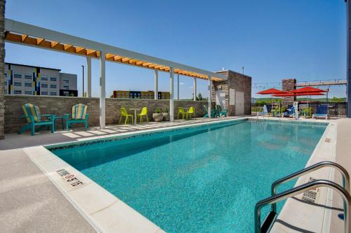 a swimming pool with chairs and tables on a building at Home2 Suites By Hilton Shepherdsville Louisville South in Shepherdsville