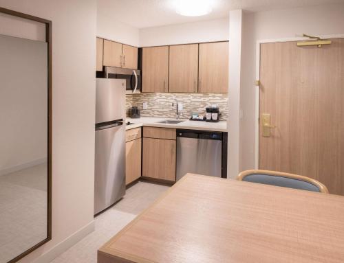 a kitchen with a refrigerator and a table with chairs at Homewood Suites by Hilton Atlanta Buckhead Pharr Road in Atlanta