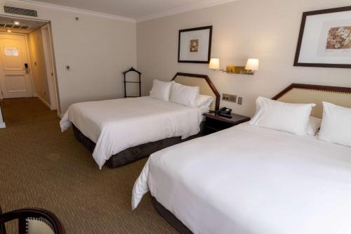 a hotel room with two beds with white sheets at Wyndham Garden Santiago Kennedy in Santiago