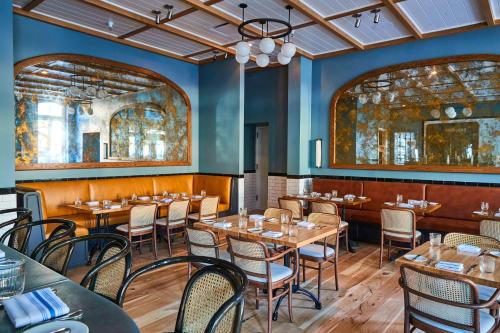 a dining room with wooden tables and chairs at The Drayton Hotel Savannah, Curio Collection by Hilton in Savannah