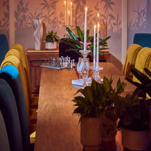 a dining room table with candles and plants on it at The Drayton Hotel Savannah, Curio Collection by Hilton in Savannah