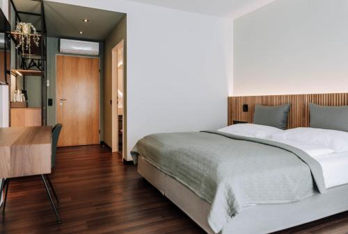 1 dormitorio con 1 cama grande y 1 mesa en HEINhotel vienna airport en Schwechat