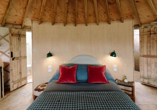 um quarto com uma cama com almofadas vermelhas em Tree Field Yurt at Moor Farm em Godshill