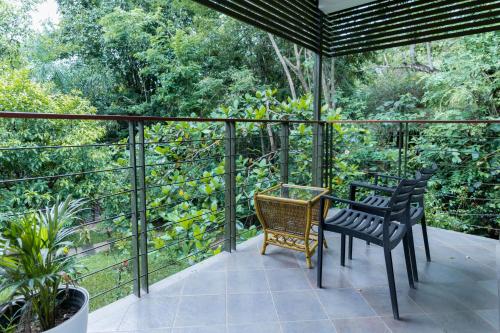 a patio with two chairs and a table on a balcony at Kuruva Island Resort And Spa - By KABINI BREEZE in Mananthavady