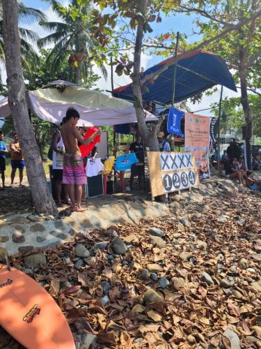 a group of people standing on a beach with leaves at La Vida Hostel in Puerto Princesa City