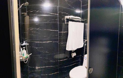 a bathroom with a toilet and a black tiled wall at Hoang Phuc Hotel Cat Ba in Cat Ba