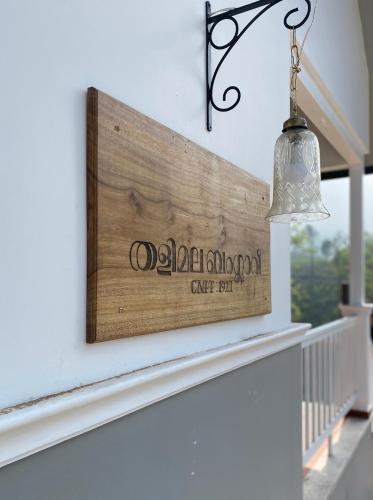 a wooden sign on a wall next to a window at THALIMALA BUNGALOW in Vythiri