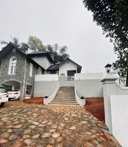 a house with a white fence and a brick driveway at THALIMALA BUNGALOW in Vythiri