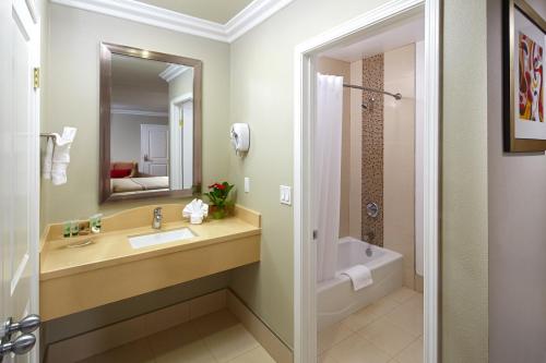 a bathroom with a sink and a tub and a mirror at Eden Roc Inn & Suites near the Maingate in Anaheim