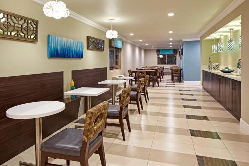 a restaurant with tables and chairs and a bar at Eden Roc Inn & Suites near the Maingate in Anaheim