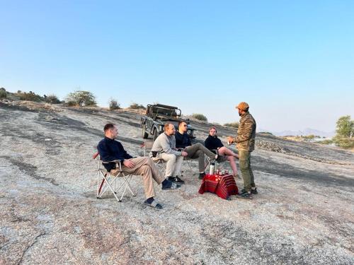 um grupo de homens sentados em cadeiras na frente de um caminhão em Jawai Greens em Jawāi Bāndh