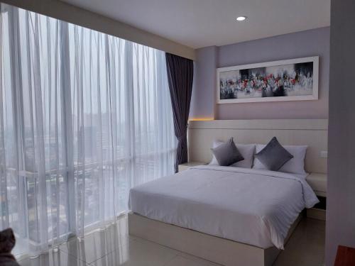 a bedroom with a bed and a large window at Daima Suites Margonda in Perhentian Pondoktjina