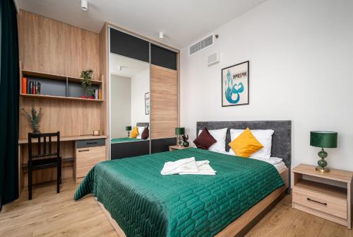 een slaapkamer met een groen bed en een bureau bij Warsview Apartments in Warschau
