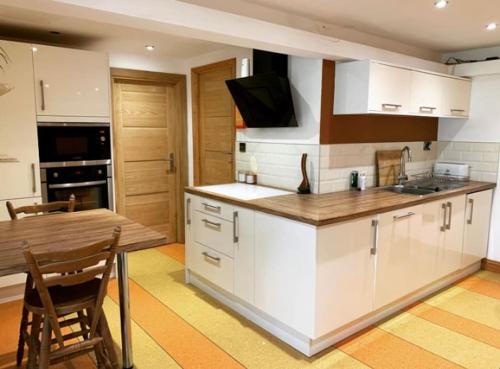 cocina con armarios blancos y mesa de madera en Self contained 1 bedroomed Annex with street parking, en Ilkeston