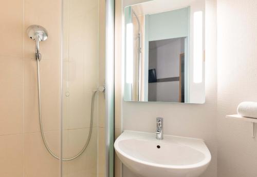 a bathroom with a sink and a shower with a mirror at B&B HOTEL Lyon Saint-Bonnet Mi-Plaine in Saint-Bonnet-de-Mure