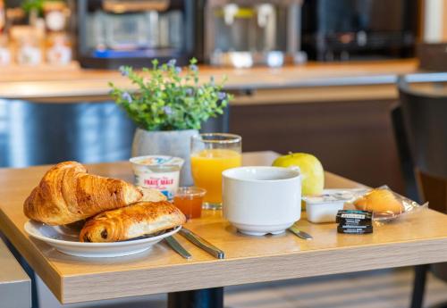 a breakfast table with a plate of bread and orange juice at B&B HOTEL Lyon Saint-Bonnet Mi-Plaine in Saint-Bonnet-de-Mure