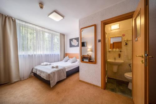 Hotel Gromada Poznań في بوزنان: غرفة نوم بسرير ومغسلة ومرحاض