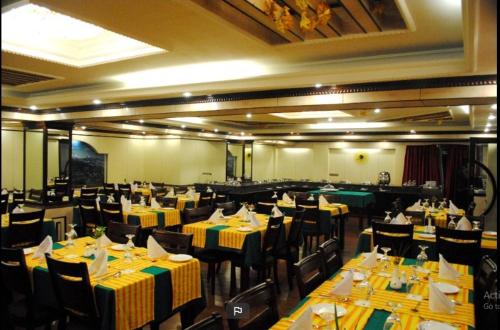 a restaurant with tables and chairs with yellow and green table settings at Darjeeling La Resort in Darjeeling