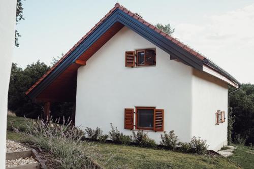 a white house with brown windows on a hill at Ecological farm Makrobios Panonija in Gornji Petrovci