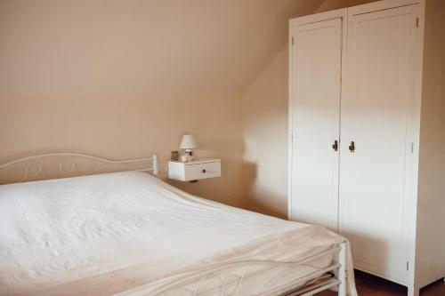 a bedroom with a white bed and a closet at Makrobios Panonija in Gornji Petrovci
