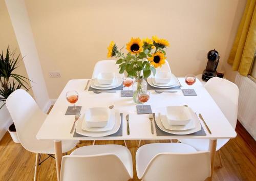 une table de salle à manger blanche avec des tournesols dans un vase dans l'établissement 2br Stylish Norwich Stay Near Cathedral Parking, à Norwich