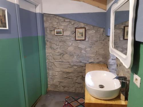 Un baño con lavabo y pared de piedra. en Hortà - Charming Attic with Rooftop Lake View, en Lezzeno