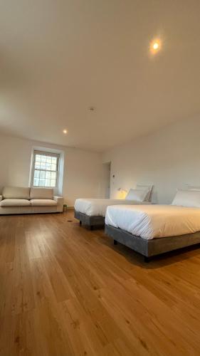 two beds in a large room with wooden floors at Matriz 55, Hostel & Suites in Ponta Delgada
