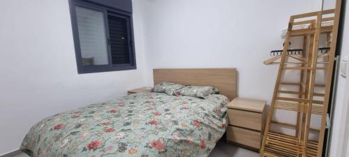 a bedroom with a bed and a ladder next to a window at Amazing apartment in Bat Yam