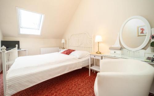 a white bedroom with two beds and a mirror at Hotel Na Skalkách in Nový Jičín