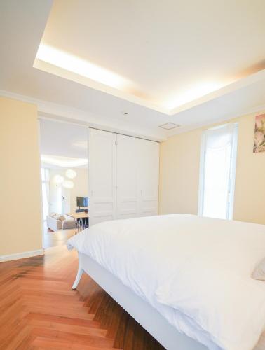 a white bedroom with a large white bed and wooden floors at Jeju Semo, Byeol in Seogwipo