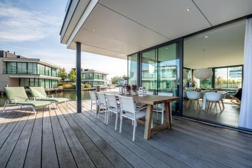 an outdoor deck with a wooden table and chairs at Harbour Villas Zeeland in Arnemuiden
