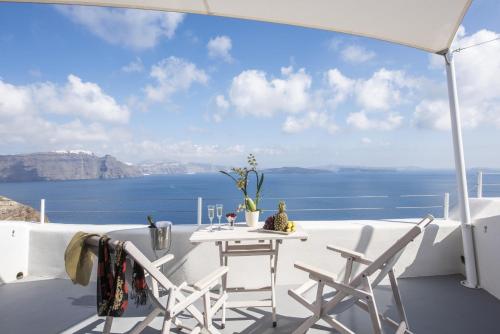 a table and chairs on a balcony with a view of the ocean at Ambition Suites in Oia