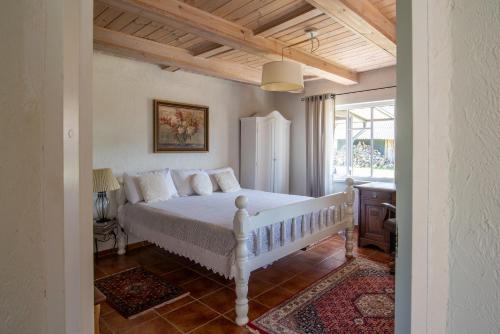 a bedroom with a white bed and a window at Dobilynė – privati ir jauki šeimos kurta sodyba 