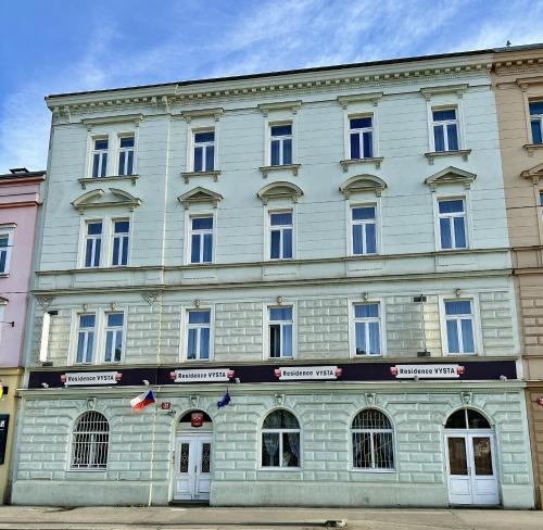 Un grand bâtiment blanc avec des fenêtres donne sur une rue. dans l'établissement Residence Vysta, à Prague