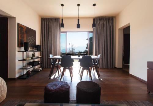uma sala de estar com uma mesa e cadeiras e uma grande janela em villa 26 em Kasauli