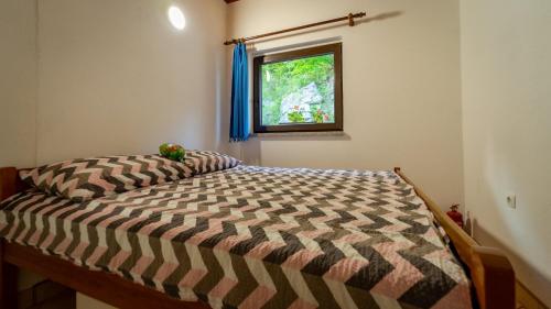 een bed in een slaapkamer met een raam bij Apartman Galerija in Lokve