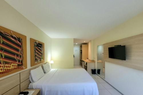 a hotel room with a bed and a flat screen tv at Praiabella Hotel in São Luís