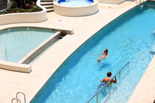 two people in a swimming pool at a resort at Monaco Caloundra in Caloundra